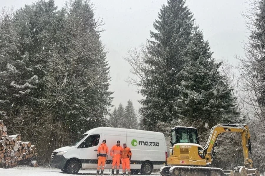 Operai vestiti di arancio in cantiere con miniescavatore e furgone